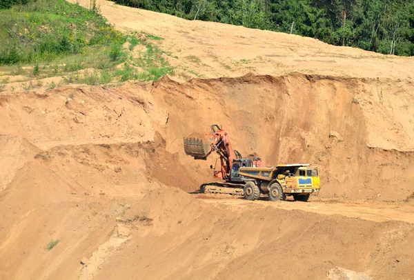 Excavator developing the sand on the opencast and loading it to the heavy dump truck. Processing of loose material in mining quarry. Drill, breaking, processing plant, crushing and screening  - Image