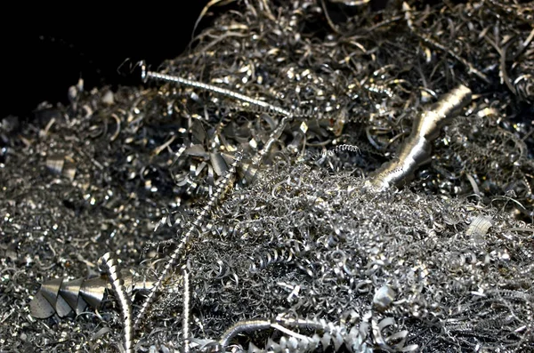 Steel scrap materials recycling. Aluminum chip waste after machining metal parts on a cnc lathe. Closeup twisted spiral steel shavings. Small roughness sharpness, possible granularity, blurred focus
