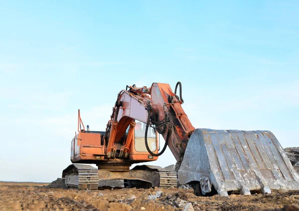 Red tracked excavator at a open-pit mining. Crushing and recycling on construction site. Road work. Special heavy construction equipment for road construction.