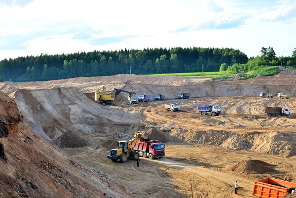 Wheel front-end loader loads sand into a dump truck. Heavy machinery in the mining quarry, excavators and trucks. Mobile jaw crusher plant with belt conveyor puts crushing and screening process