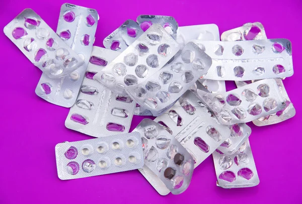 Many plastic pharmaceutical packaging for tablets and medicines drugs on the purple background. Heap of medical pills in package. Concept of healthcare and medicine