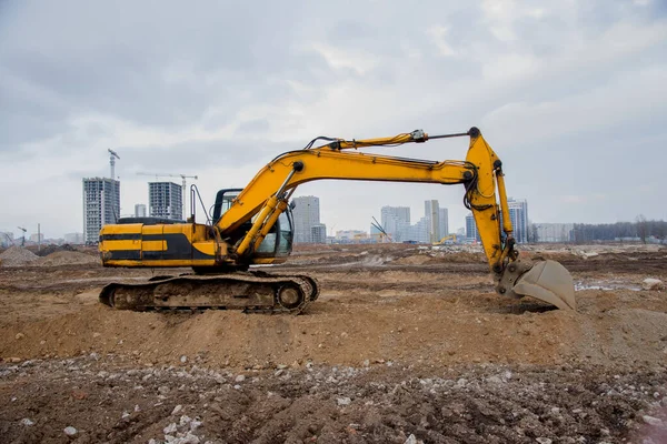 Excavators at earthworks on construction site. Backhoe loader digs a pit for the construction of the road. Digging trench for laying sewer pipes drainage in ground. Earth-Moving Heavy Equipment