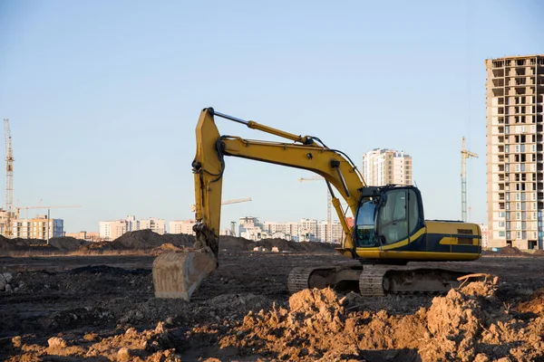 Excavator working at construction site. Backhoe digs ground for the foundation and for paving out sewer line. Construction machinery for excavating, loading, lifting and hauling of cargo on job sites