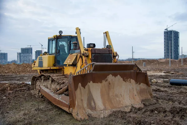 Bulldozer during land clearing and foundation digging at large construction site. Crawler tractor with bucket for pool excavation and utility trenching. Dozer, Earth-moving equipment.