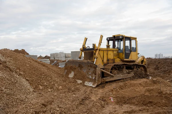 Bulldozer during land clearing and foundation digging at large construction site. Crawler tractor with bucket for pool excavation and utility trenching. Dozer, Earth-moving equipment