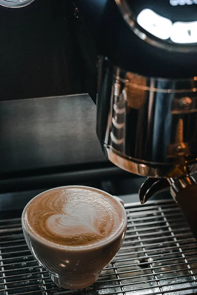 Espresso makinesinin üzerinde Latte Art olan bir fincan kahve.
