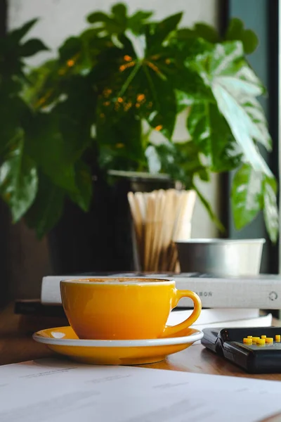 Kahve dükkanındaki Pencere Masasında Sarı bir fincan kahve.