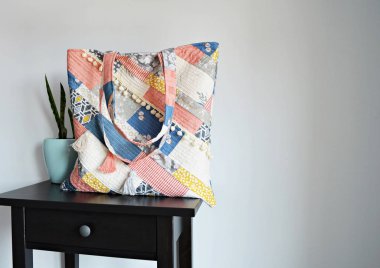 Quilted boho tote bag, house plant in mint pot and black table over white