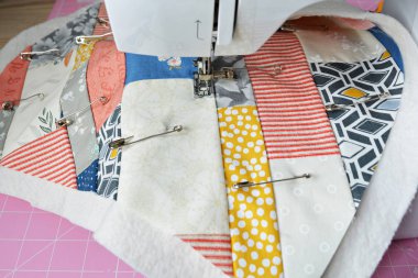 Working process: quilt, metal pins and sewing machine