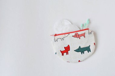 Köpekler, pamuk tomurcukları ve makyaj diskleriyle dolu el yapımı yuvarlak bir çanta.