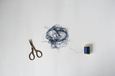 Mavi arapsaçı makarası ve makas beyazın üzerine