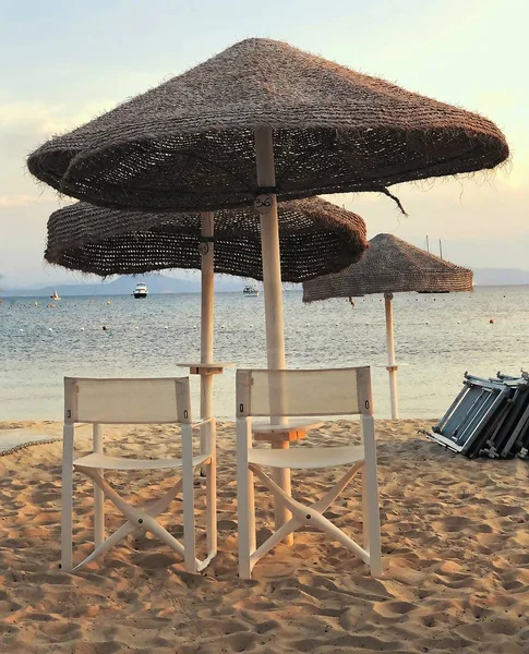 Strandszene Bei Sonnenuntergang Mit Sonnenschirm Und Weißen Liegestühlen — Stockfoto