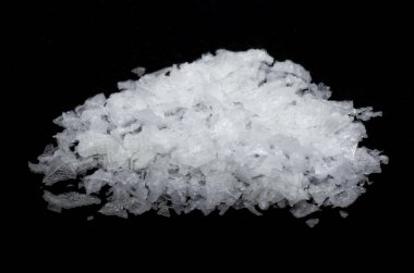 Siyah arka plan makrofotografı üzerine hafif çözünürlüklü Maldon tuzu. Saflık.