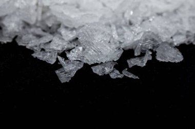 Siyah arka plan makrofotografı üzerine hafif çözünürlüklü Maldon tuzu. Saflık.