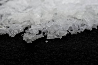 Siyah arka plan makrofotografı üzerine hafif çözünürlüklü Maldon tuzu. Saflık.