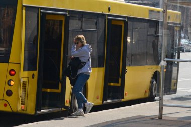 KYIV, UKRAINE - 25 Mart 2020 - COVID-19 Coronavirus salgınıyla bağlantılı olarak karantina sırasında Ukrayna 'nın başkenti Kyiv, tıbbi maskeli insanlar otobüse biniyor