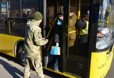 KYIV, UKRAINE - 25 Mart 2020 - İnsanlar COVID-19 Coronavirus salgınıyla bağlantılı olarak karantina sırasında Ukrayna 'nın başkenti Kyiv' e binmelerine izin vermeden önce belgeleri kontrol eden bir polis memuruyla konuşuyor