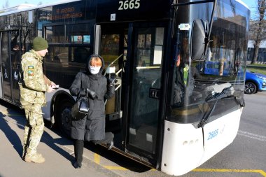 KYIV, UKRAINE - 25 Mart 2020 - İnsanlar COVID-19 Coronavirus salgınıyla bağlantılı olarak karantina sırasında Ukrayna 'nın başkenti Kyiv' e binmelerine izin vermeden önce belgeleri kontrol eden bir polis memuruyla konuşuyor