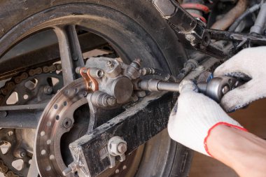 Bir motosiklet üzerinde fren balataları değiştirme işlemi.