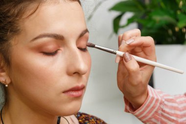 Makyaj yapma süreci. Modelin yüzünde bir fırça ile çalışan makyaj sanatçısı.