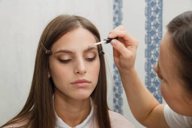 Makyaj yapma süreci. Modelin yüzünde bir fırça ile çalışan makyaj sanatçısı.