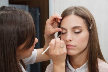 Makyaj yapma süreci. Modelin yüzünde bir fırça ile çalışan makyaj sanatçısı.