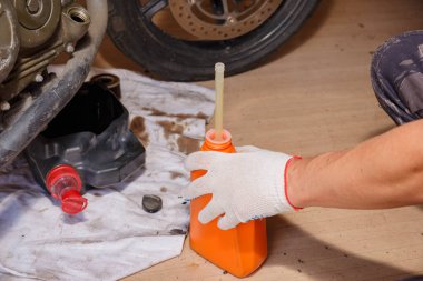 Motosiklet motoruna yeni yağ dökme süreci.