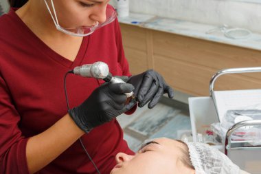 Usta, müşteriye daktiloyla kaş makyajı yapar..