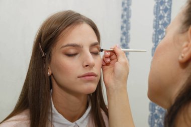 Makyaj yapma süreci. Modelin yüzünde bir fırça ile çalışan makyaj sanatçısı.