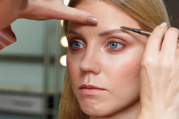 Makeup artist emphasizes eyebrows on model\'s face.