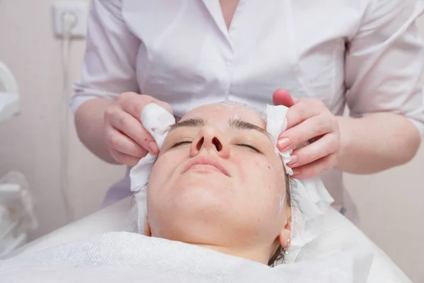 Esteticista lava o rosto da mulher usando almofadas de algodão. Preparação para um rosto de limpeza — Fotografia de Stock