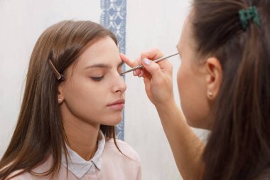 Makyaj yapma süreci. Makyaj sanatçısı bir bru ile çalışıyor