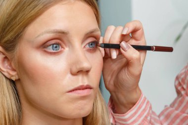 Makyaj sanatçısı modelin yüzünde eyeliner oluşturur.