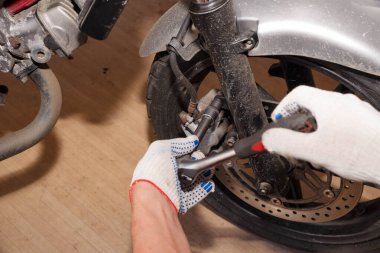 Bir motosiklet üzerinde fren balataları değiştirme işlemi.