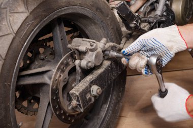 Bir motosiklet üzerinde fren balataları değiştirme işlemi.