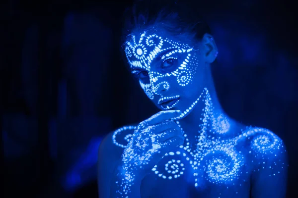 Body art on the body and hand of a girl glowing in the ultraviolet light.