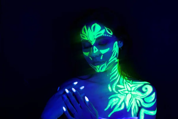 Body art on the body and hand of a girl glowing in the ultraviol