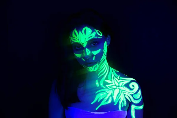 Body art on the body and hand of a girl glowing in the ultraviol