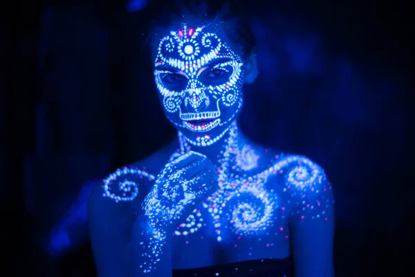 Body art on the body and hand of a girl glowing in the ultraviolet light.