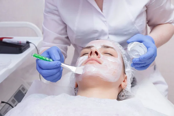 Crop master applying white mask with brush on face and neck of y — Stock Photo, Image