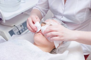 Güzellik uzmanı pamuk pedkullanarak kadının yüzünü yıkar. Temizleme yüzü için hazırlık.