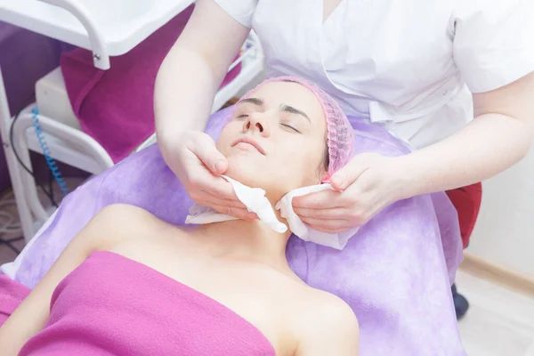 The master conducts the face preparation procedure. Preparation of the client for buccal massage.. cosmetologist makes a buccal massage of the patient\'s facial muscles.