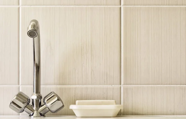 Grifos de agua, y una barra de jabón sobre un fondo de una pared de azulejos . —  Fotos de Stock