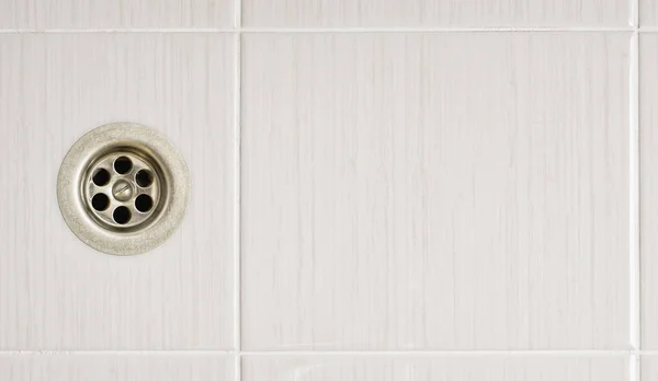Het afvoer gat in een badkamer met betegelde vloeren — Stockfoto