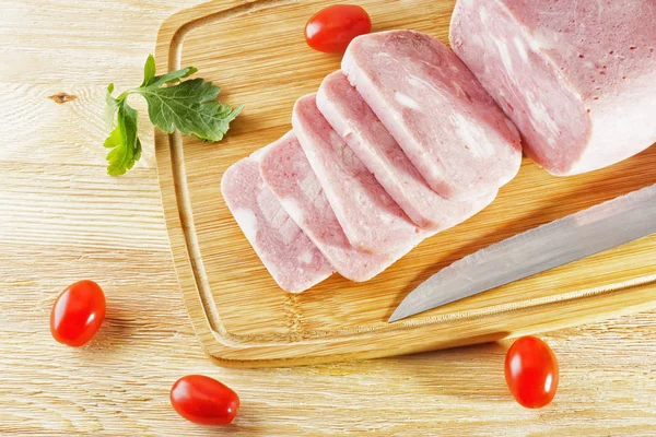 A piece of ham and tomatoes lying on a wooden table — Stock Photo, Image