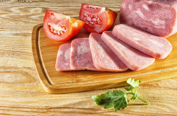 Ham and tomatoes lying on wooden background — Stock Photo, Image