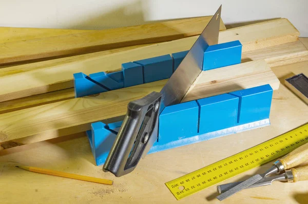 Serrar peças em um ângulo usando uma caixa de mitra e uma serra . — Fotografia de Stock