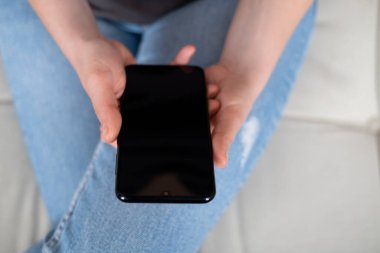 Mobil ekran akıllı telefonunda uygulama kullanan genç bir kadın. Teknoloji kullanımı, internetten alışveriş, mobil uygulamalar, mesajlaşma, bağımlılık, video çağrısı, geçiş. Evde çalış.. 