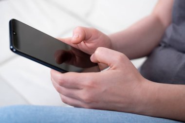 Mobil ekran akıllı telefonunda uygulama kullanan genç bir kadın. Teknoloji kullanımı, internetten alışveriş, mobil uygulamalar, mesajlaşma, bağımlılık, video çağrısı, geçiş. Evde çalış.. 