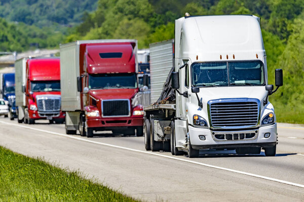 A solid line of eighteen-wheelers barrel down an interstate highway in east Tennessee
